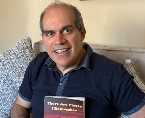 Mike Dileo '89 in blue polo shirt, holds a copy of his book - "There are Places I Remember."