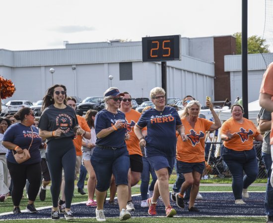 Crowd of people running onto the field at Homecoming 2025