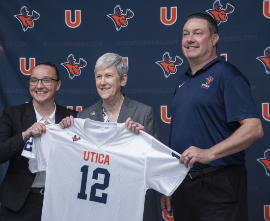 Kristin St. Hilaire, Stephanie Nesbitt, and Damian Boehlert hold up a Utica Pioneers jersey.